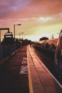 Train at railroad station against sky during sunset