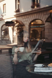 Woman drinking water from while sitting at table