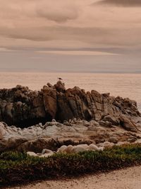 Rocks on sea shore against sky during sunset