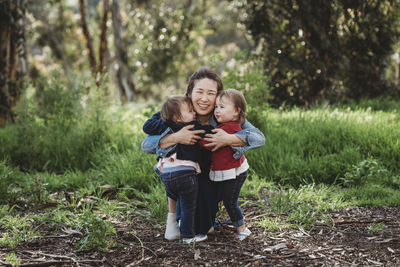 Portrait of mother hugging twin daughters outside