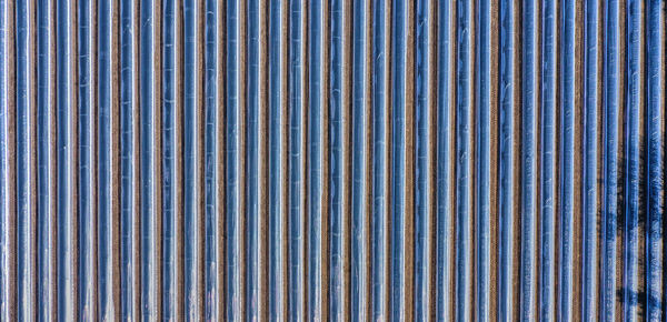 Full frame shot of metal fence against blue wall