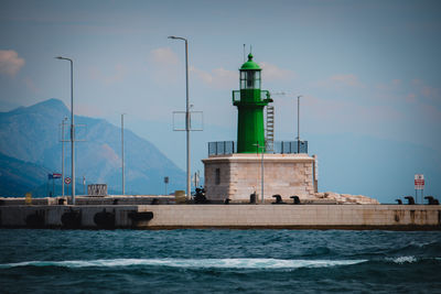 Lighthouse by sea against clear sky