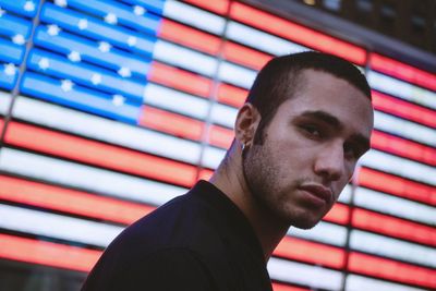 Portrait of young man standing against american flag