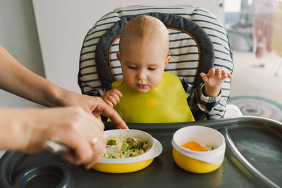 Little child with solid nutrition. baby girl eating food and mix vegetable plate