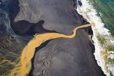 Aerial view of braided orange river flowing into ocean in southe