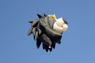 Low angle view of hot air balloon flying against clear blue sky