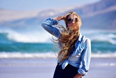 Mid adult woman with tousled hair standing at beach