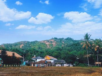 Houses and trees on field against sky