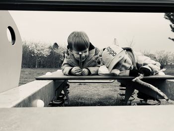 Portrait of boy sitting against sky