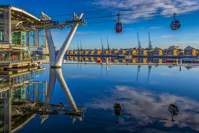 Cranes at riverbank against blue sky