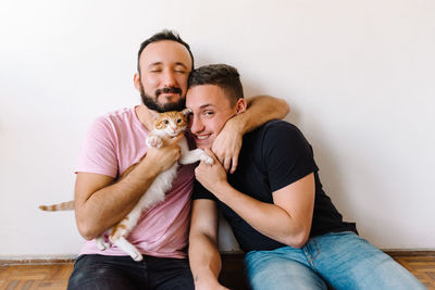 Gay couple playing with kitten.