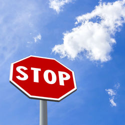 Low angle view of road sign against blue sky