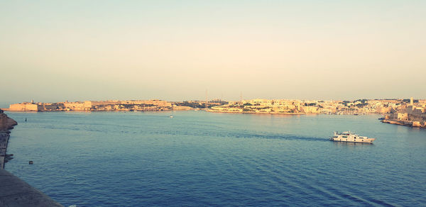 Scenic view of sea and buildings against clear sky