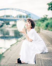 Side view of young woman holding while sitting outdoors