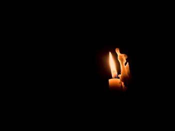 Candle burning against black background