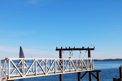 View of bridge over sea against clear blue sky