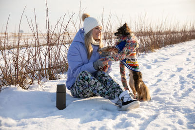 Full length of woman sitting on snow