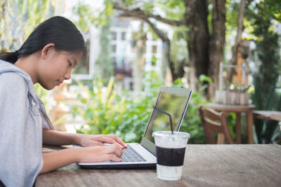 Side view of woman using laptop at table