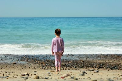 Rear view of girl standing at beach