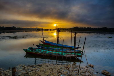 Fishing boat on beach against sky during sunset