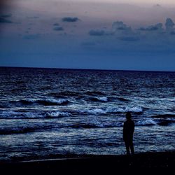 Silhouette of people standing on beach at sunset