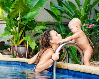 High angle view of mother playing with daughter while swimming in pool