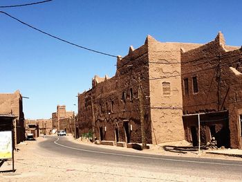 Street amidst buildings against clear blue sky