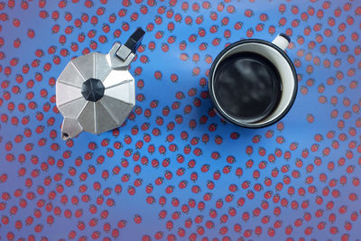 High angle view of coffee cup and pot on patterned table