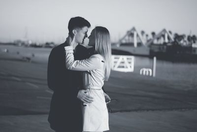 Couple standing on bridge against water