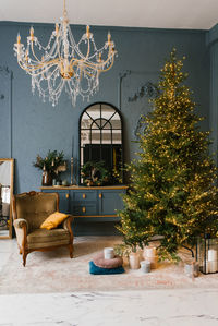 Stylish classic interior of the living room with a christmas tree, an armchair with pillows
