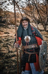 Portrait of smiling warrior standing in forest