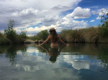 Rear view of mid adult woman standing in lake