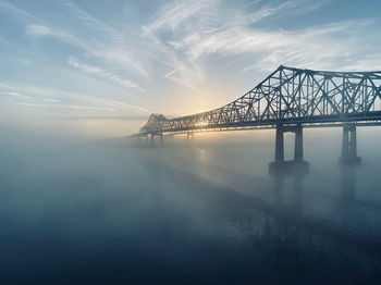 Bridge over sea against sky during sunset