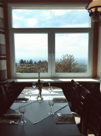 Empty chairs and table against sky seen through window