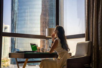 Rear view of woman using laptop at home