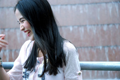 Portrait of smiling young woman against wall