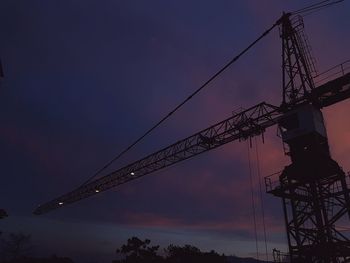 Low angle view of electricity pylon against sky at sunset