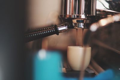 Close-up of coffee pouring in cup from machinery at cafe