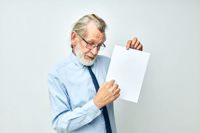 Portrait of businessman holding paper against white background