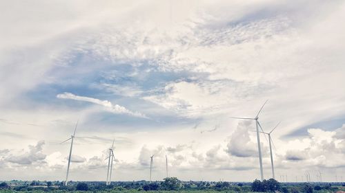 Low angle view of wind turbines against sky