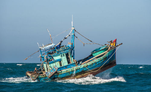 Fishing boat in sea against clear sky