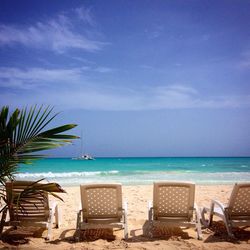 Chairs at beach against blue sky