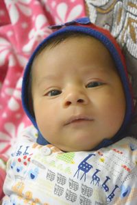 High angle portrait of cute baby boy lying on bed at home