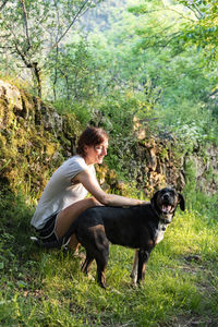 Woman petting and playing with her dog in a forest.