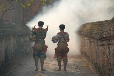 Rear view of people in costume walking on walkway