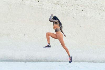 Side view of woman running on wall