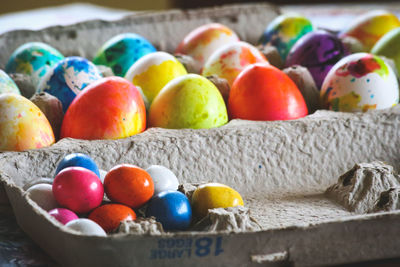 Brightly dyed easter eggs in an egg carton alongside candy of the same colors.