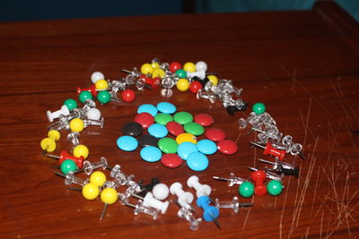 Colorful candies with thumbtacks on wooden table