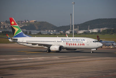 Airplane on airport runway against sky