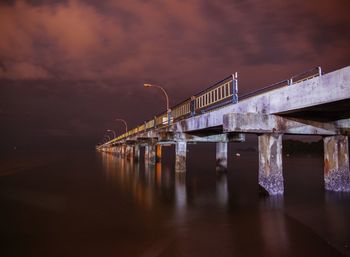 Illuminated bridge over water in city at night